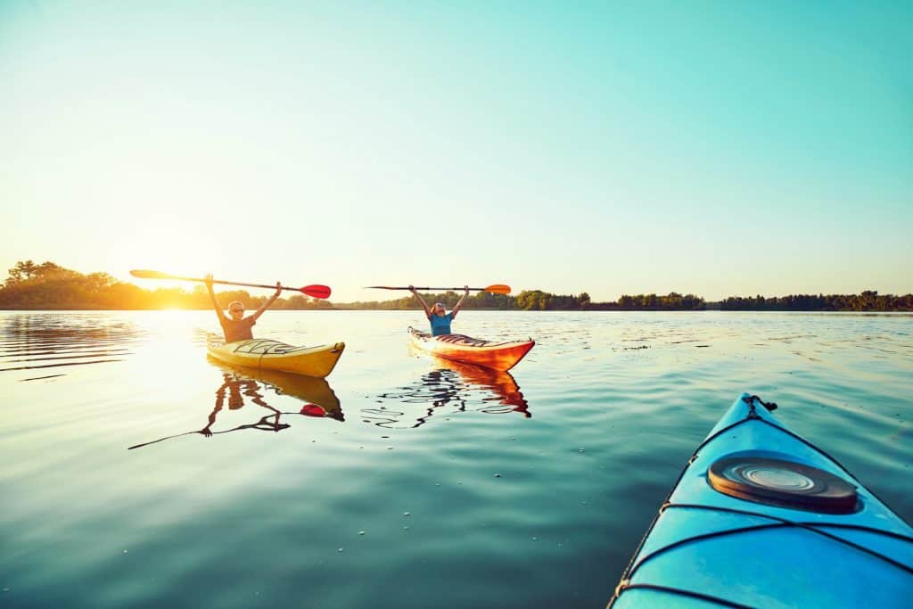 three kayak on the water at sunset