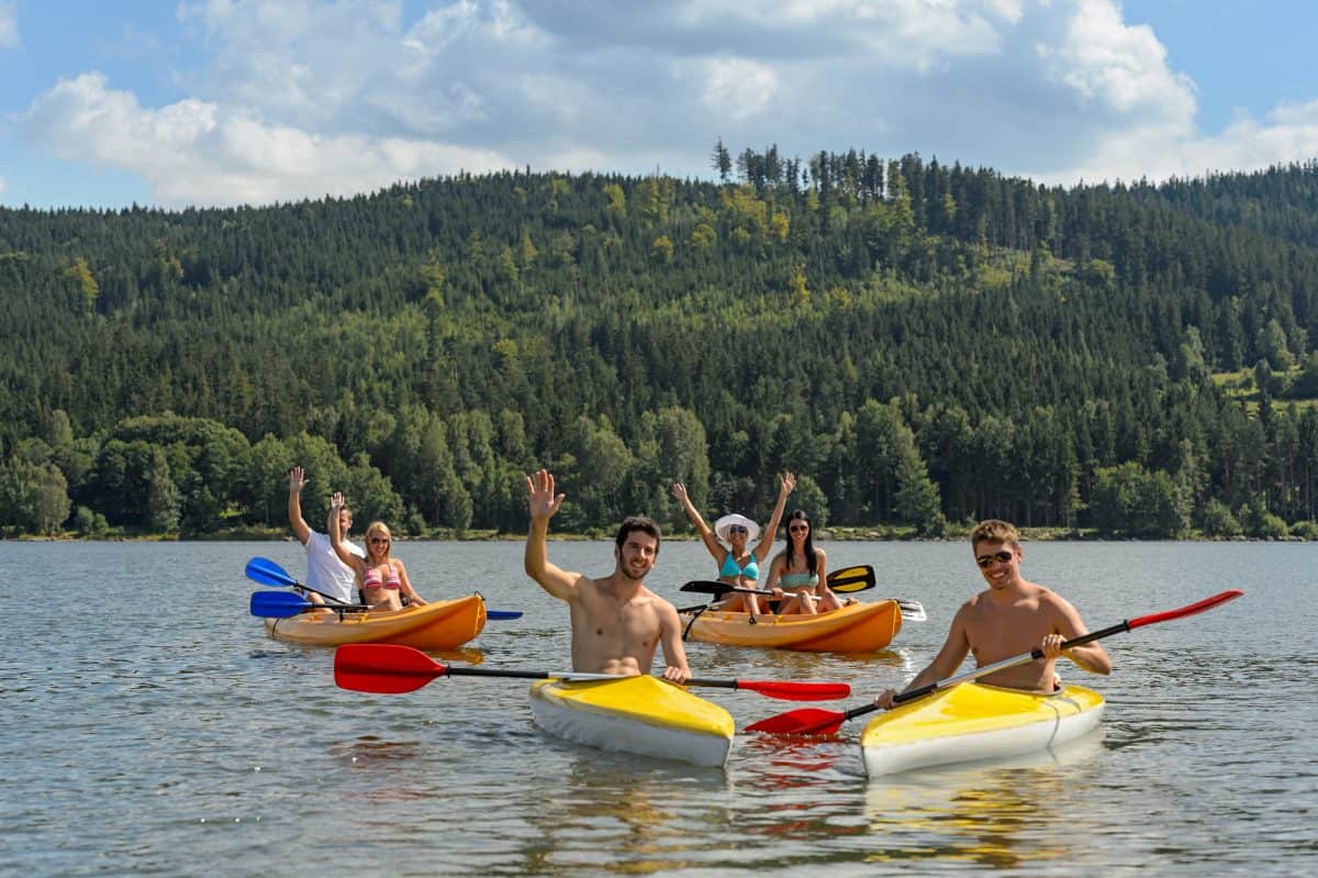 cheerful friends in kayaks summer